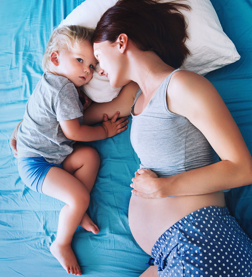 schwangere Mutter mit Kleinkind auf dem Bett